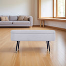 BANCO EN TELA BEIGE CON PATAS NEGRAS CON CASQUILLOS DORADOS